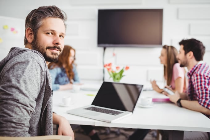 Portrait of confident young male executive with colleagues in meeting at creative office